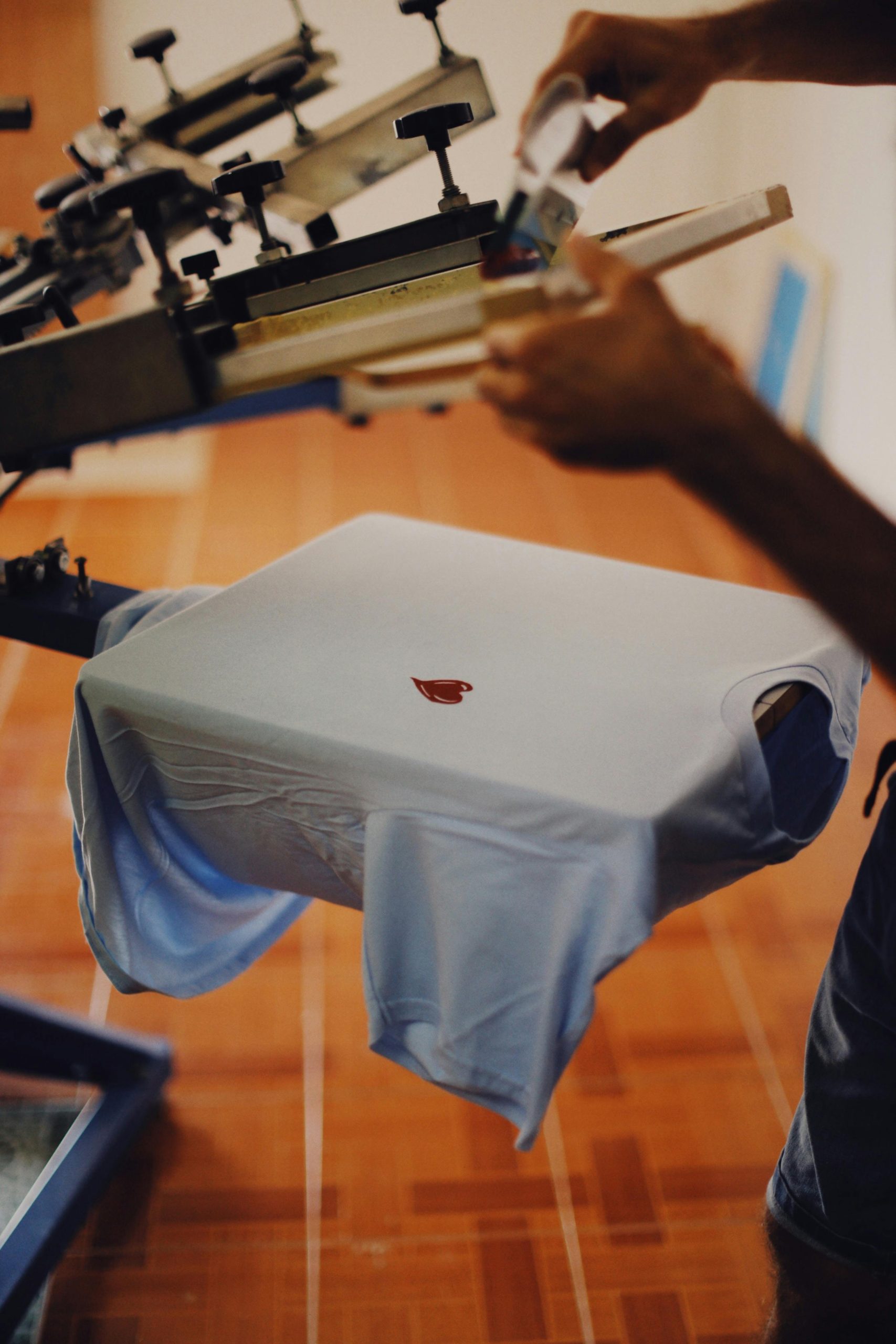 T-Shirt wird auf einer Siebdruckmaschine mit Logo bedruckt